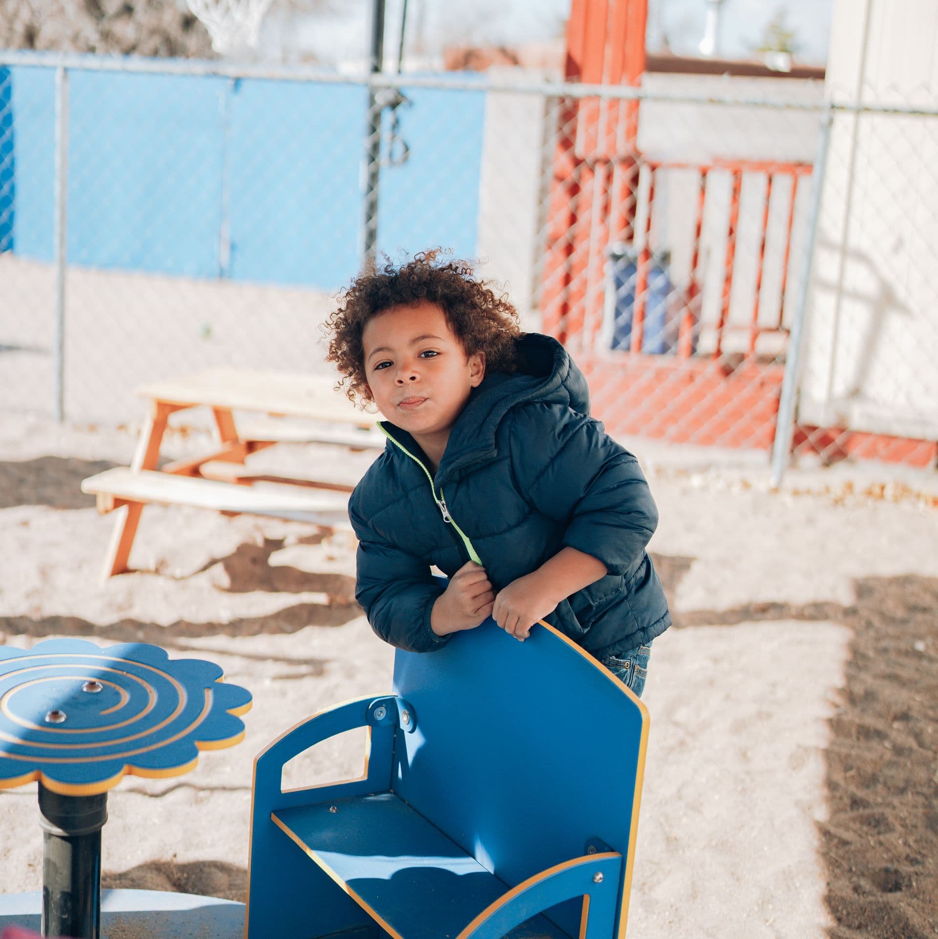 Child playing safely in a fenced ABQ Childcare playground